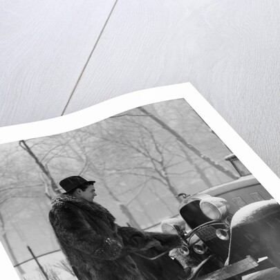 1930s Man In Hat And Raccoon Fur Coat Standing Foot On Bumper Of Chevrolet Roadster Stalled In Snow Storm by Anonymous
