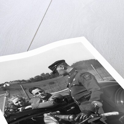 1930s Couple In Convertible Coupe Stopped By Motorcycle Cop Checking License Of Driver by Anonymous