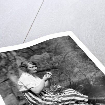 1920s Young Woman In Striped Skirt Sitting On Stream Bank In Woods Braiding Garland Of Wild Flowers by Anonymous