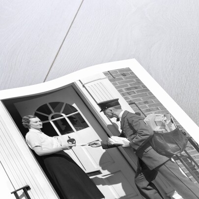1930s Postman Giving A Letter To A Woman In The Doorway Of A Colonial Brick Home by Anonymous