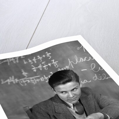 1920s 1930s Boy At Desk In Classroom In Front Of Blackboard Shooting Paper Wad With Rubber Band by Anonymous