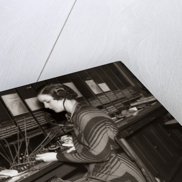 1930s Woman Telephone Operator Sitting At Large Manual Switchboard Directing Calls by Anonymous