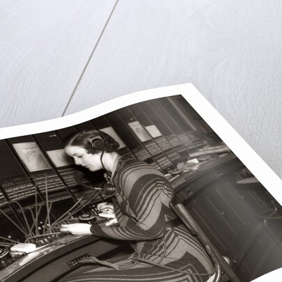 1930s Woman Telephone Operator Sitting At Large Manual Switchboard Directing Calls by Anonymous