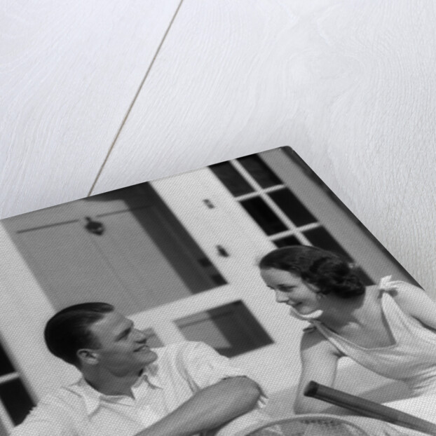 1930s Couple Man Woman In Tennis Whites Holding Racquets Sitting Talking On Steps In Front Of House Outdoor by Anonymous