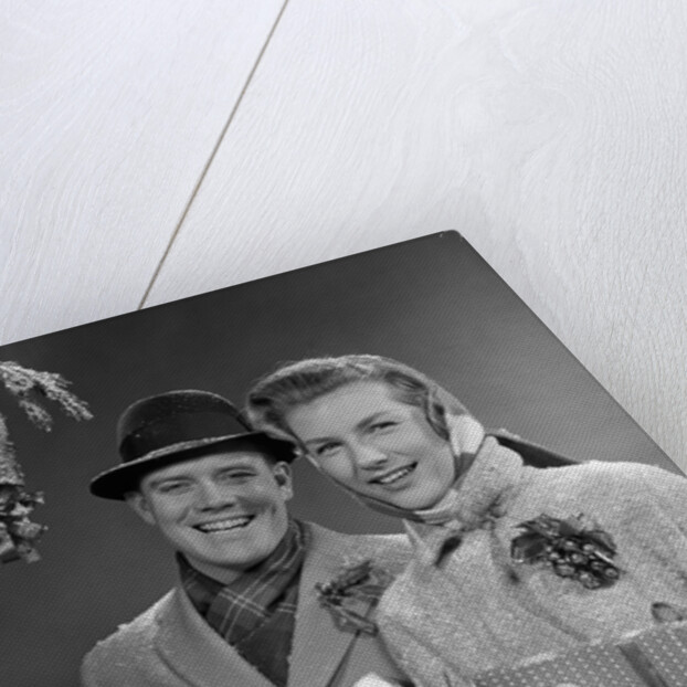 1950s Husband And Wife Carrying Armload Of Christmas Packages Standing In Snow Under Porch Light by Anonymous