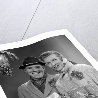 1950s Husband And Wife Carrying Armload Of Christmas Packages Standing In Snow Under Porch Light by Anonymous