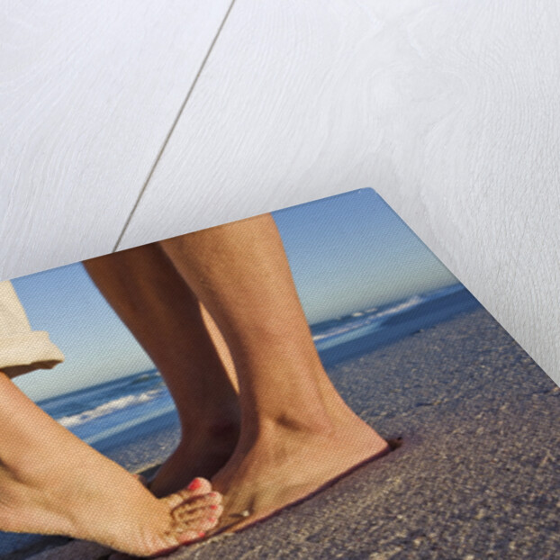 Feet of couple hugging on beach by Anonymous