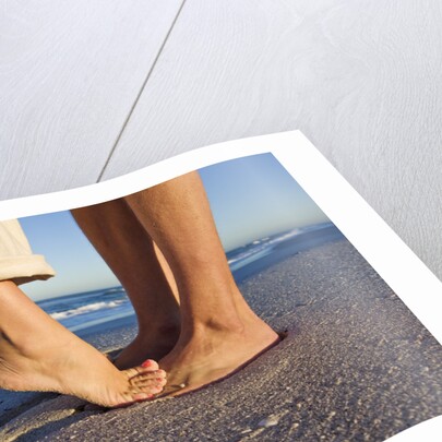 Feet of couple hugging on beach by Anonymous