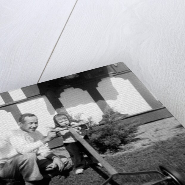 A father show his two year old daughter how to mow the lawn, ca. 1956 by Anonymous