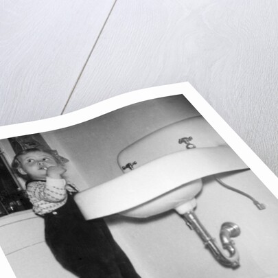 A young girl brushes her teeth at the sink, ca. 1955 by Anonymous