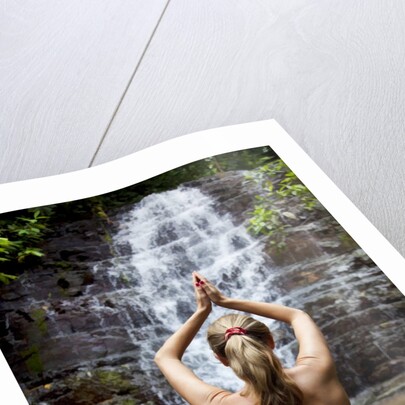 Woman meditating in front of a waterfall by Anonymous