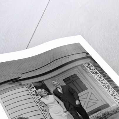 Mature couple walking on sidewalk front of house by Anonymous