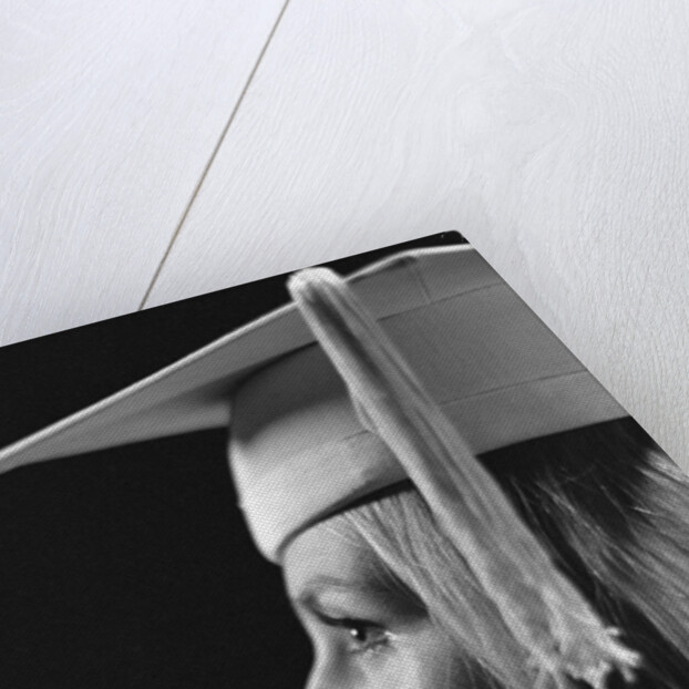 Profile blond female graduate wearing white mortarboard by Anonymous