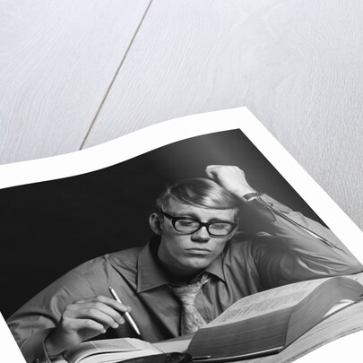 Young man studying reading books leaning on arm by Anonymous