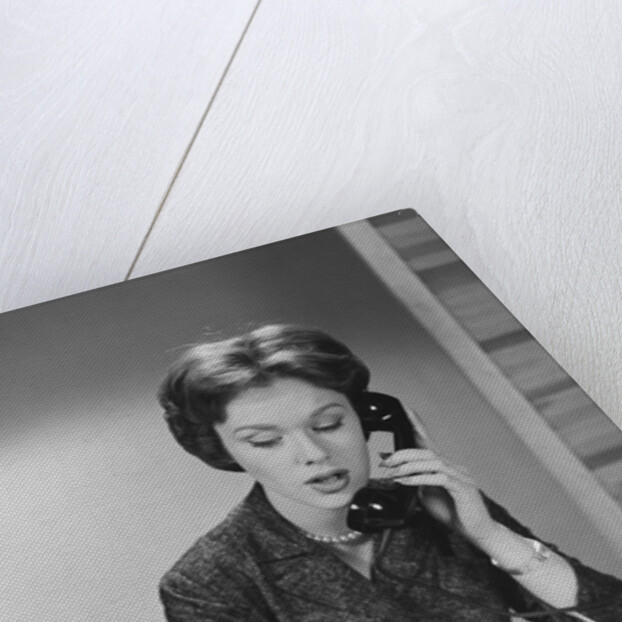Brunette business woman sitting desk talking telephone writing note on calendar by Anonymous