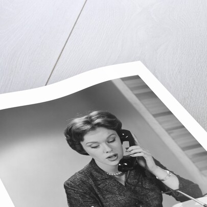 Brunette business woman sitting desk talking telephone writing note on calendar by Anonymous