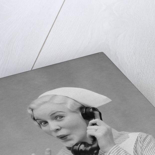 Smiling blond nurse with surprised expression talking on telephone holding up two fingers by Anonymous