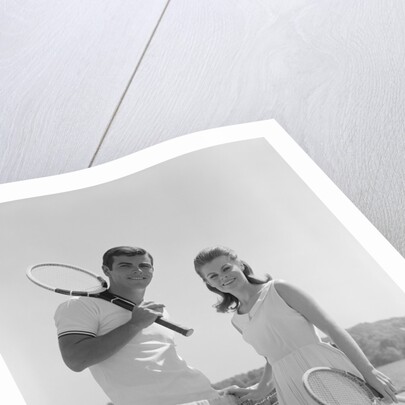 Portrait tennis couple man woman holding racquets standing by net by Anonymous