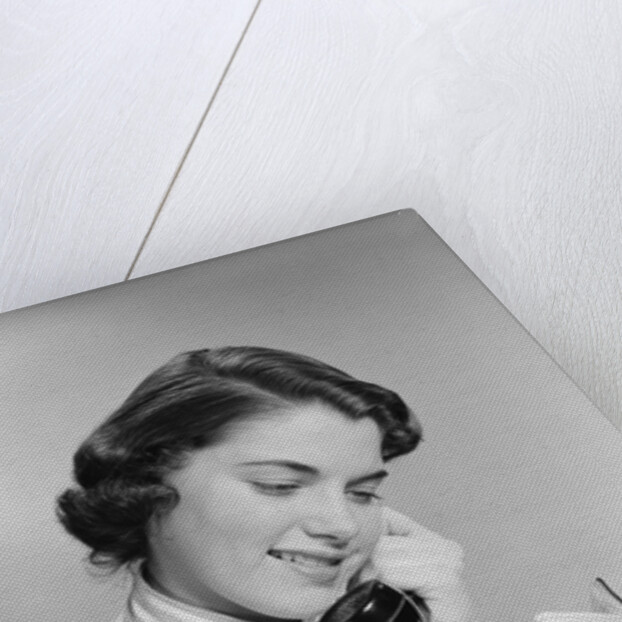 Young woman talking on telephone reading address from little black book by Anonymous