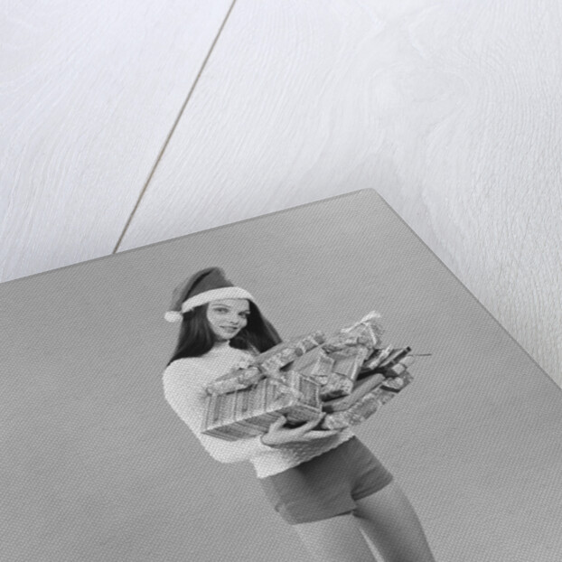Young woman wearing santa claus hat hot pants go-go boots holding wrapped christmas presents by Anonymous