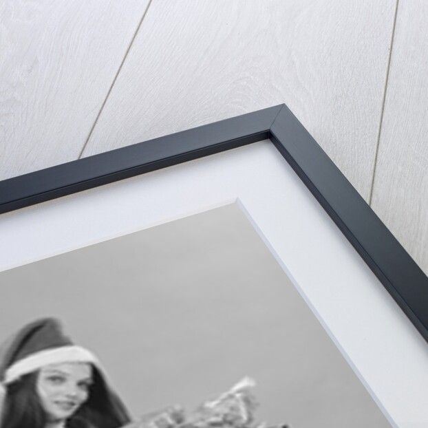 Young woman wearing santa claus hat hot pants go-go boots holding wrapped christmas presents by Anonymous