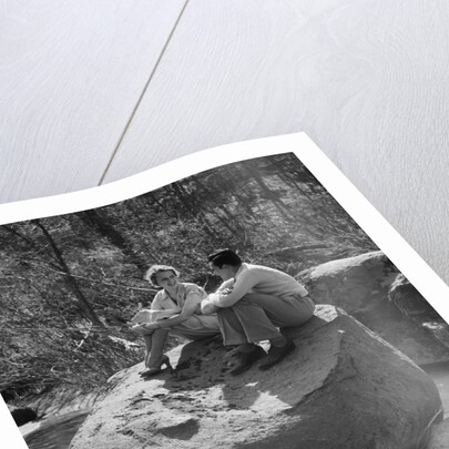Couple man woman sitting on large rock in stream hugging knees smiling happy romance by Anonymous