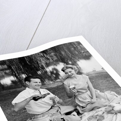 Man woman couple having a summer picnic outdoors drinking beer by Anonymous