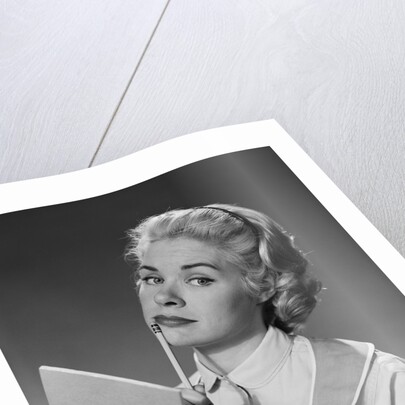 Blond woman wearing apron writing pad in hand pencil to chin thinking by Anonymous