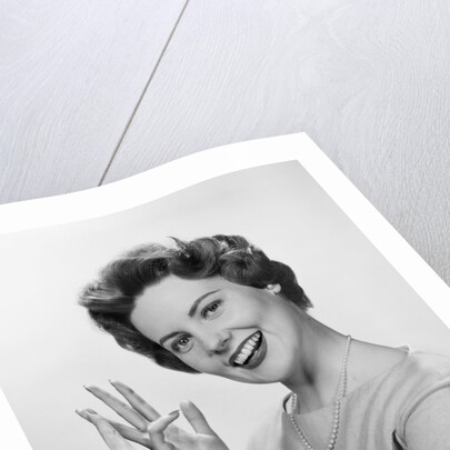 Smiling woman counting on fingers wearing pearls by Anonymous