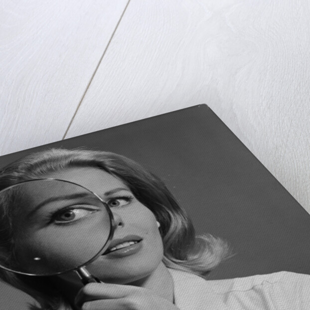 Blond woman magnifying glass held up to and enlarging one eye by Anonymous