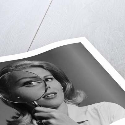 Blond woman magnifying glass held up to and enlarging one eye by Anonymous