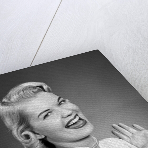 Woman wearing pearls smiling with hands up thumbs tucked under arm by Anonymous