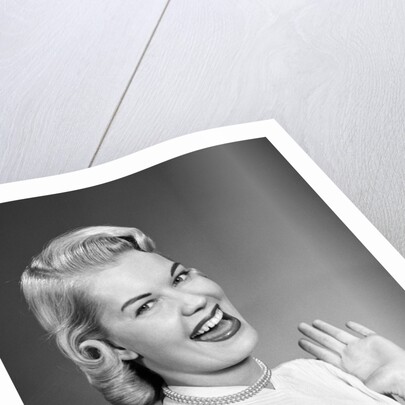 Woman wearing pearls smiling with hands up thumbs tucked under arm by Anonymous