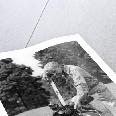 Elderly man in yard kneeling down to fix lawnmower by Anonymous