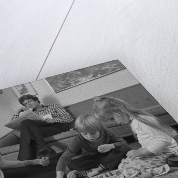 Family mother kids playing board game living room floor father reading newspaper by Anonymous
