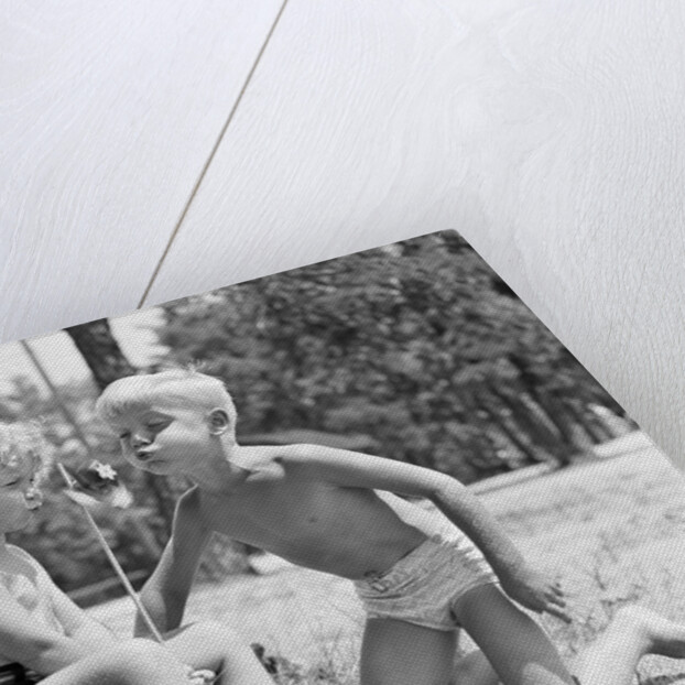 Blonde boy girl wearing bathing suits blowing on a pinwheel toy summer by Anonymous