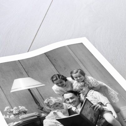 Father reading to family in chair by Anonymous