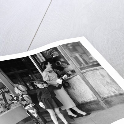 Mother and 2 children buying tickets to movie matinee boy wearing cowboy costume by Anonymous
