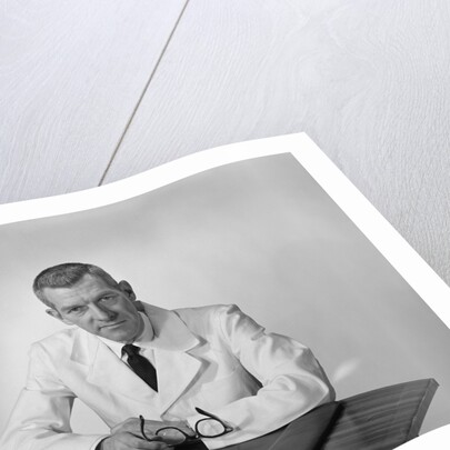 Portrait male doctor sitting at desk serious expression by Anonymous
