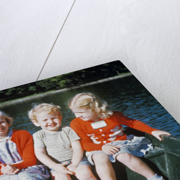 Boy and two girls in red sweaters sitting in back of rowboat by Anonymous