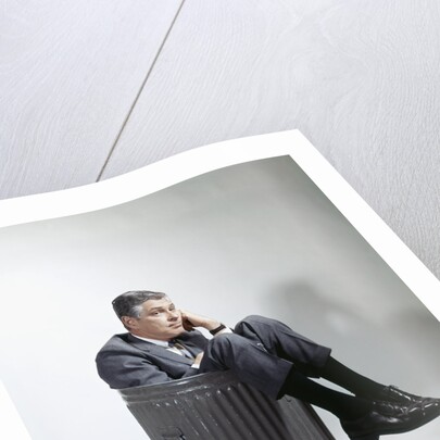 Sad man in business suit sitting in trash garbage can by Anonymous