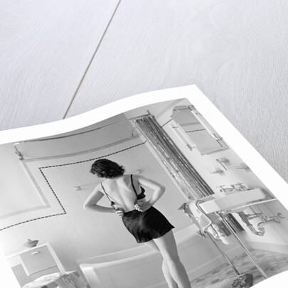 Back view of woman in bathroom fastening black bra by Anonymous