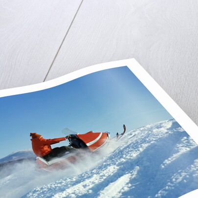 Man wearing red jacket and hat driving snowmobile by Anonymous
