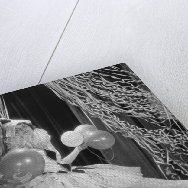 Woman dressed in harlequin costume sitting on stack of balloons by Anonymous