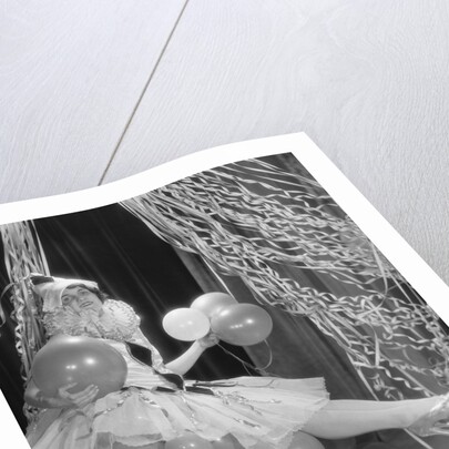 Woman dressed in harlequin costume sitting on stack of balloons by Anonymous