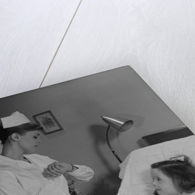 Woman nurse checking pulse taking temperature on little girl patient in hospital bed by Anonymous