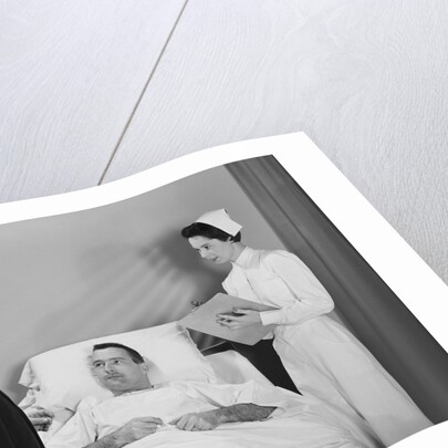 Man doctor woman nurse talking with male patient lying in hospital bed by Anonymous