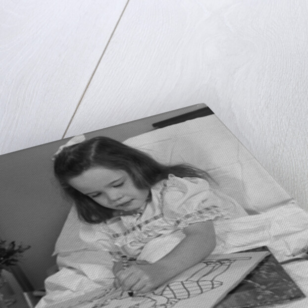 Little girl patient in hospital bed writing in coloring book by Anonymous