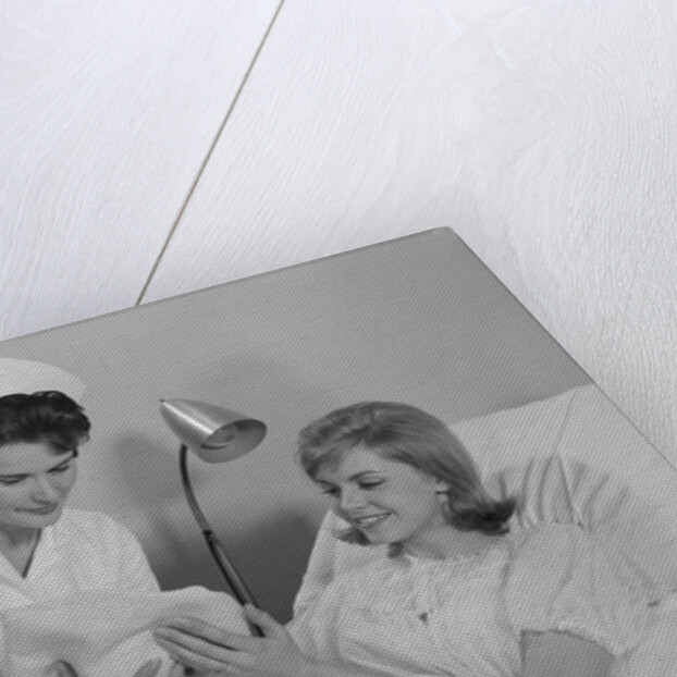 Woman nurse giving baby to smiling mother patient sitting in hospital bed by Anonymous