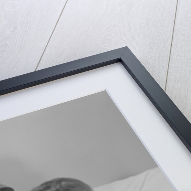 Woman nurse giving baby to smiling mother patient sitting in hospital bed by Anonymous